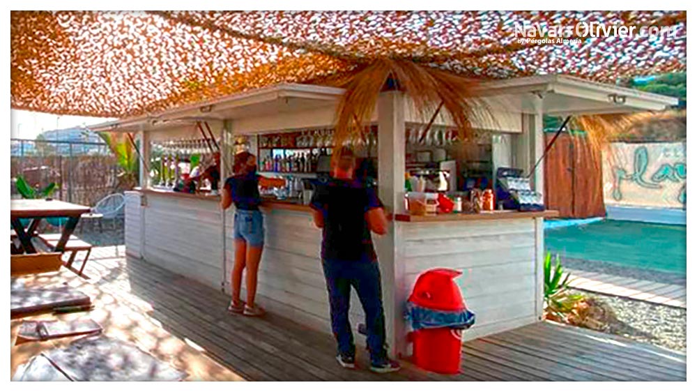 Quiosco de madera con techo decorado en carritx y sombraje de red de camuflaje